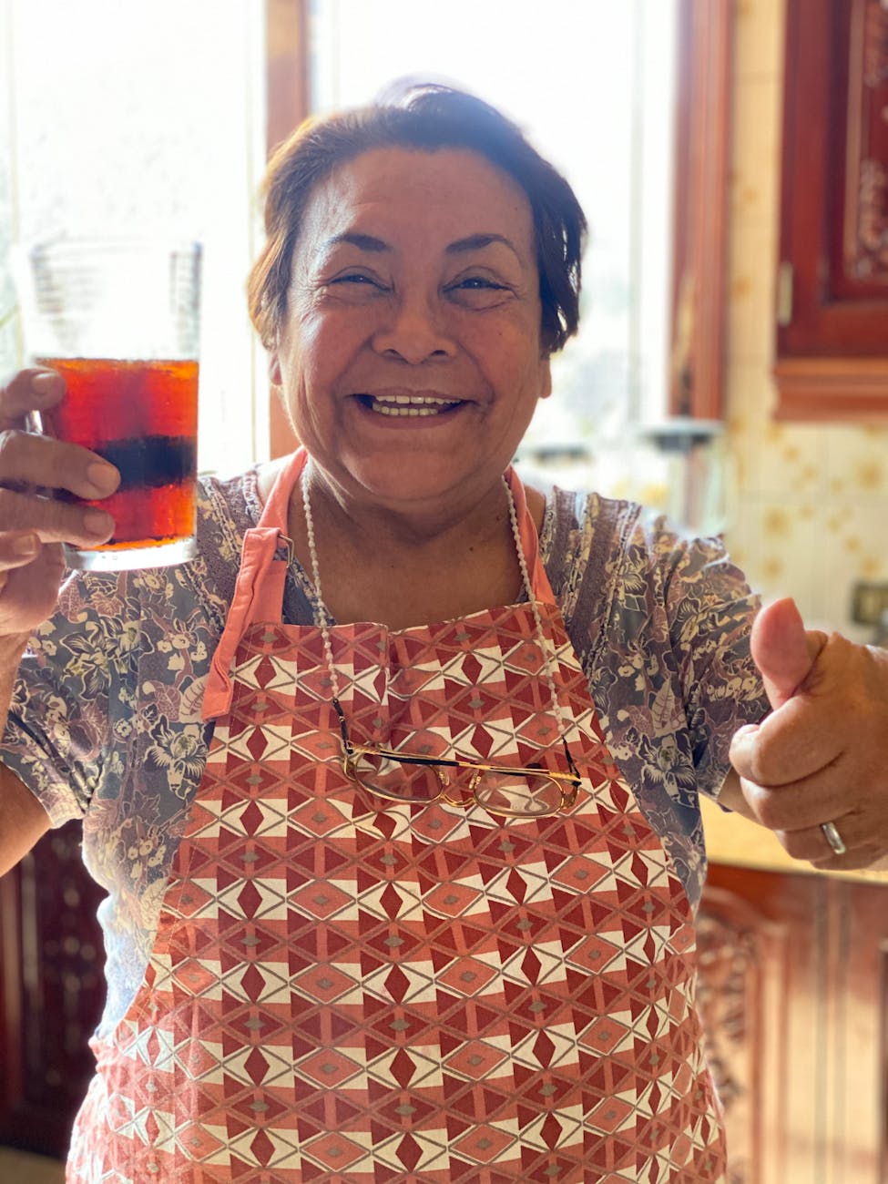 Mujer mayor sonriente en su cocina, preparando un remedio casero